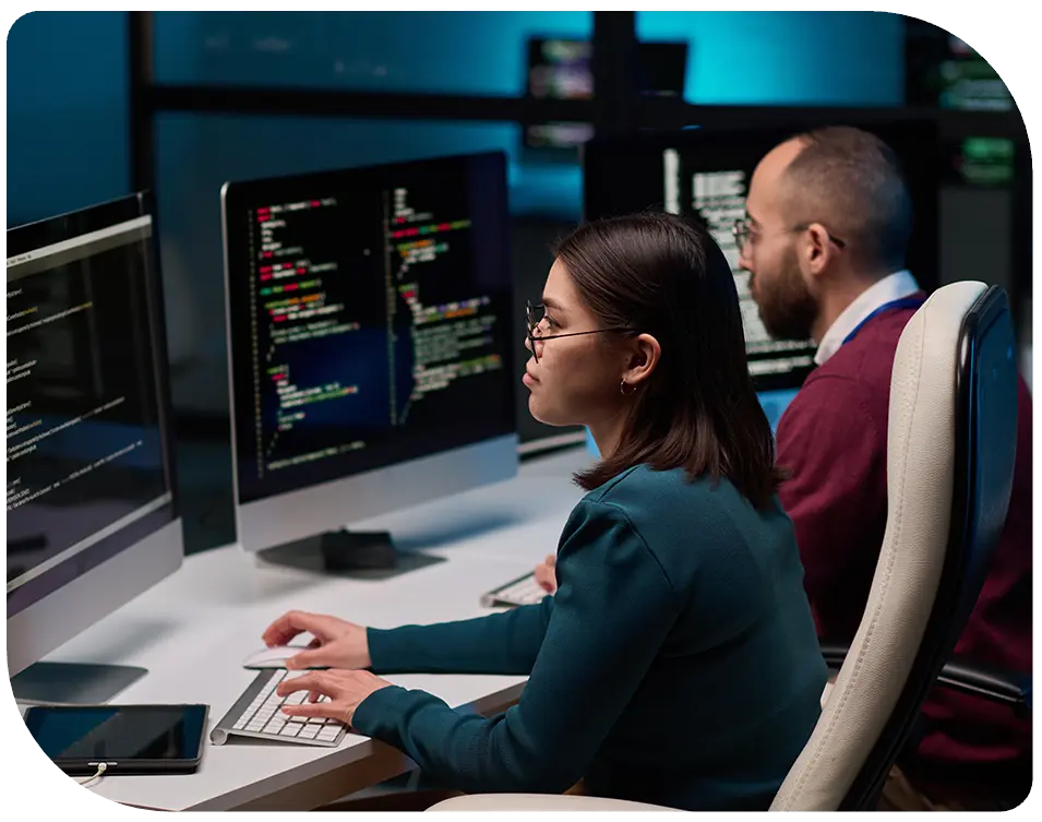 two data center employees typing on keyboards and looking at monitors